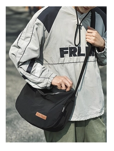 Detail of black nylon crescent bag with embossed logo and metal zipper in outdoor usage