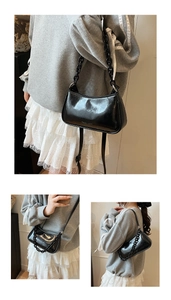 Detail of black glossy hobo bag featuring chunky acrylic chain and adjustable strap