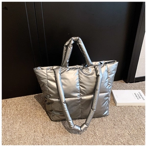 Détail d'un sac cabas argenté matelassé avec finition métallisée et doubles poignées