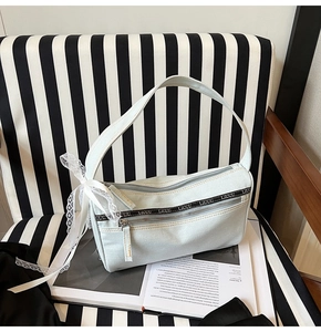 Detail view of denim baguette bag with side lace bow and LIUU logo strap detail