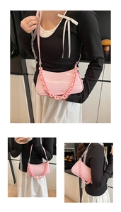 Detailed macro of pink patent leather underarm bag with thick chain and brand logo