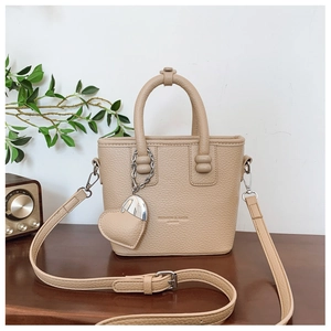 Detail der beigen Handtasche mit Herzanhänger auf einer vintage Holzoberfläche