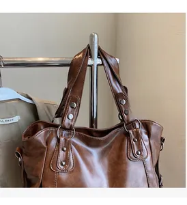 Detailed close-up of brown vintage leather tote bag handles and metallic rivets