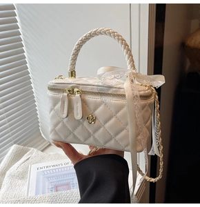 Detail of white quilted box bag with floral gold hardware and lace ribbon bow accent