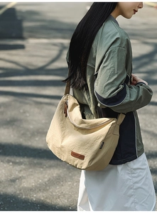 Detail of khaki nylon crescent bag showing logo patch and adjustable wide strap