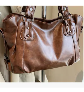 Detail of vintage brown tote bag showing soft synthetic leather texture and metal rings
