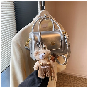 Detailed view of silver square bag with a cute teddy bear charm and golden hardware