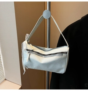 Detail of light blue denim baguette bag with lace bow and double zipper branding
