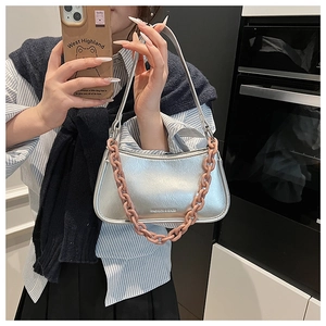 Close-up of a silver handbag with bold orange-pink chain and mirror selfie perspective