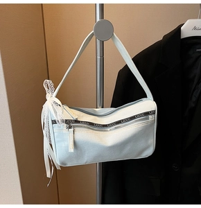 Close-up of light blue denim baguette bag with lace bow and logo webbing strap