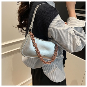 Detail of silver crescent underarm bag with decorative pink chain and metallic leather