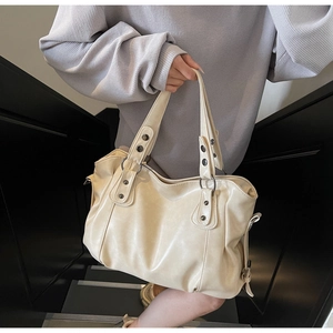 Close-up of retro cream tote bag featuring vintage metal rivets and leather texture