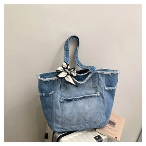 Détail du grand sac cabas en denim bleu avec bords effilochés et foulard en soie décoratif