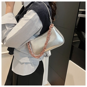 Close-up of silver crescent bag with litchi texture and pink chain strap on model