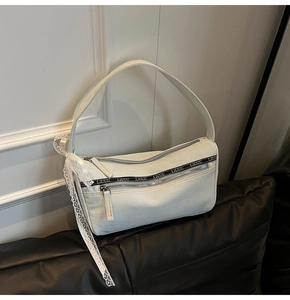 Detail of light blue denim baguette bag with dual zippers, logo strap and lace ribbon