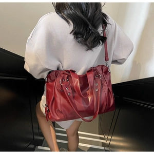 Burgundy tote bag in soft leather with metal rivets shown on a model at stairs