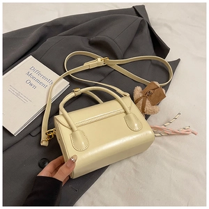 Close-up of a creamy white mini handbag featuring a cute plush bear charm on the side