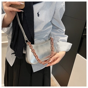Detail of silver metallic hobo bag featuring a decorative pink acrylic chunky chain