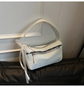 Detail of light blue denim baguette bag with LIIUU letter ribbon and white lace bow