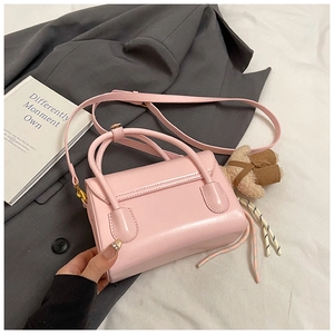 Pink minimalist crossbody bag with dual top handles and brown plush bear charm detail
