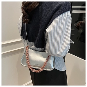 Detail view of silver pebble texture crossbody bag with pink chain and fashion text