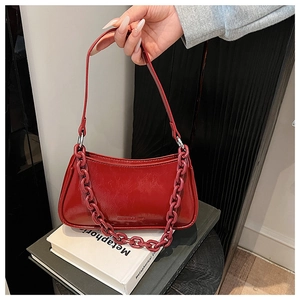 Detail of red patent leather dumpling bag with chunky resin chain and brand lettering