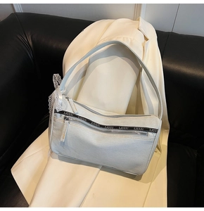 Detail of off-white denim shoulder bag featuring a lace bow and LIUUU logo webbing