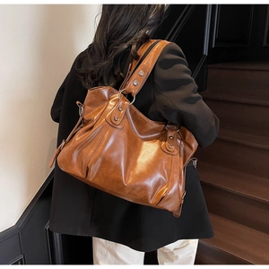 Close-up of a vintage brown tote bag worn over the shoulder with sleek black blazer