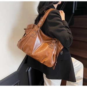 Brown vintage faux leather tote bag showing side capacity and wide strap on shoulder