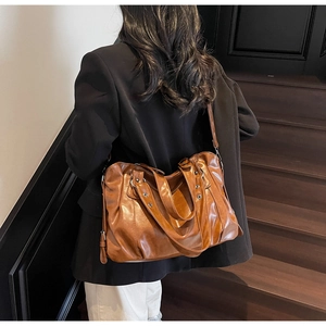 Detail view of caramel brown faux leather tote with vintage texture and silver rivets