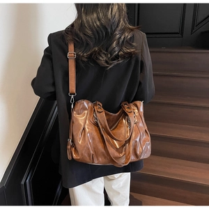 Detailed view of the pleated brown PU leather texture and adjustable strap of the tote bag