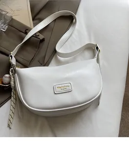 Détail du sac demi-lune blanc en similicuir avec pendentif baseball et cordon tressé