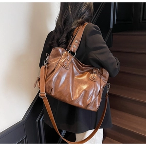 Detail view of large brown faux leather tote bag worn as a shoulder bag on a model