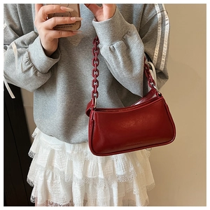 Close-up of red glossy patent leather underarm bag with thick fashion chain strap
