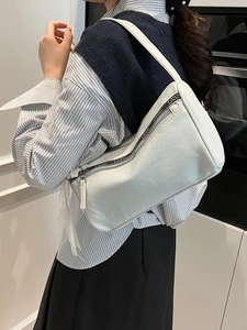 Light blue denim baguette bag with lace ribbon detail and logo strap over shoulder