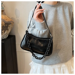 Detail of black glossy patent leather bag with acrylic chain and crossbody shoulder strap