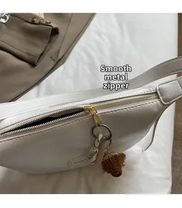 Détail du zip doré fluide sur un sac en cuir PU blanc avec charme de baseball design