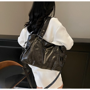 Rear view of a model wearing a black vintage tote bag with rivets and adjustable strap