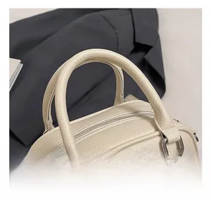 Detail shot of cream leather bowling bag featuring litchi texture and silver hardware