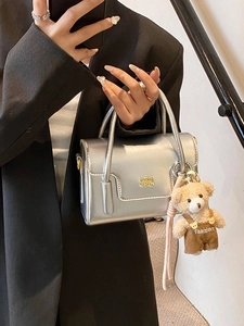 Chic silver metallic mini handbag with gold logo and plush bear charm for women