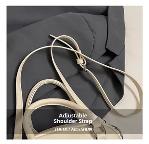 Detail of adjustable shoulder strap and silver metal hardware on cream pillow bag
