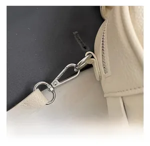 Macro detail of silver metal hook and zipper on white lychee grain leather handbag