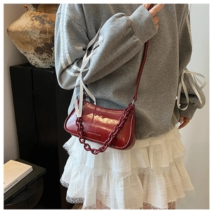 Detail of red patent leather dumpling bag with chunky chain strap and crossbody style