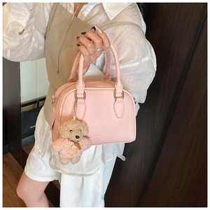 Detail of pink bowling bag with pebble leather texture and a cute knitted bear charm