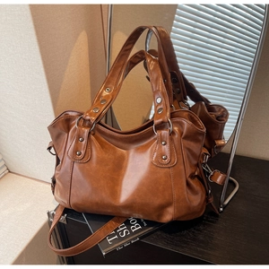 Close-up of vintage brown PU leather tote bag with metallic rivet details and adjustable strap