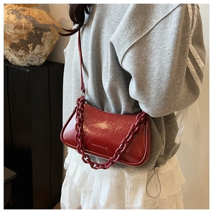 Detailed view of brick red patent leather crossbody bag with a thick decorative chain