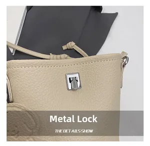 Dettaglio macro della chiusura argentata e motivo cucciolo su borsa in pelle beige
