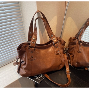 Detailed shot of brown vintage tote bag with metal rivets and adjustable shoulder strap