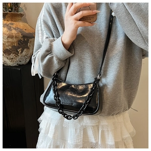 Detail of glossy patent leather bag with embossed logo and chic black chain strap