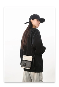 Side view of white tactical messenger bag with black mesh pocket on model
